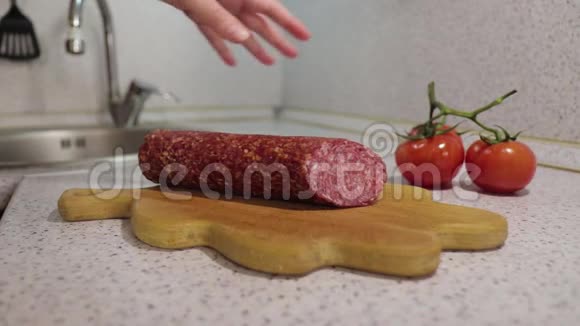 小女孩的手用西红柿在木砧板上切了一根熏香肠视频的预览图