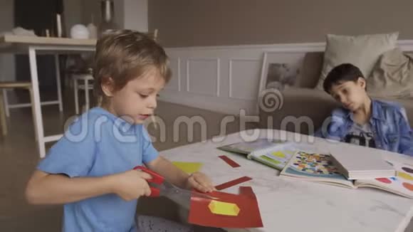 专心致志的5岁男孩用剪刀热情地剪纸伸出舌头集中5岁男孩剪纸视频的预览图