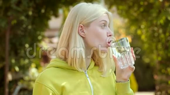 美女从绿色公园的玻璃上喝水清洁卫生水视频的预览图