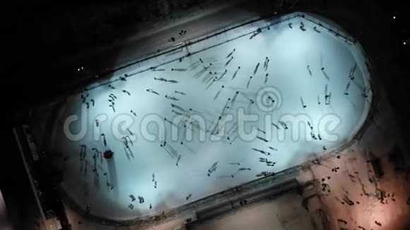 人们在夜间在明亮的冰场上滑冰空中自上而下的视野视频的预览图