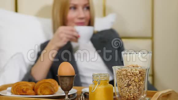 年轻漂亮成功的商务女性在豪华酒店房间吃早餐在轻酒店公寓享受的女孩视频的预览图