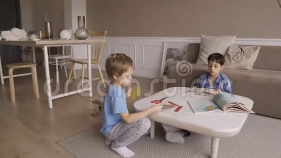 专心致志的5岁男孩用剪刀热情地剪纸伸出舌头集中5岁男孩剪纸视频的预览图