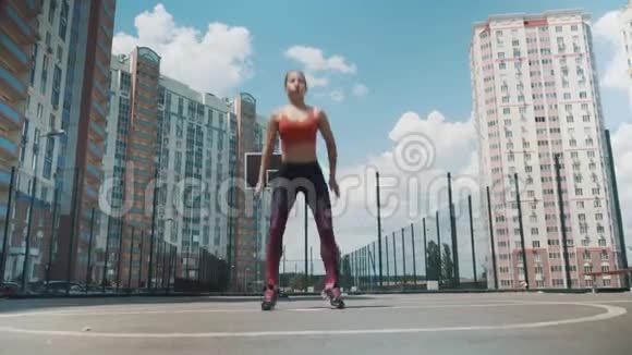 年轻的运动女孩做运动蹲与维普瑞加在街上健身背景中的高层建筑视频的预览图