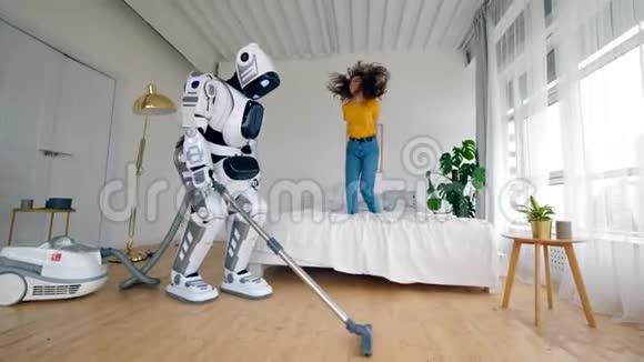 年轻的女人在床上跳跃机器人在盘旋智能家居概念视频的预览图