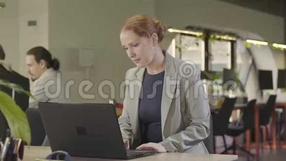 集中白人中年妇女在笔记本电脑键盘上打字的特写智能女性办公室画像视频的预览图