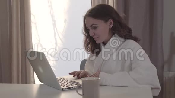 年轻漂亮的白人女孩在家上网的肖像漂亮的黑发女人用笔记本电脑做脸视频的预览图