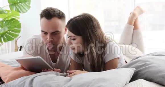 一对夫妇在床上用数码平板电脑接收坏消息视频的预览图
