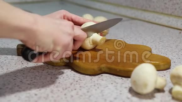年轻女孩的手在木切割板上剪了一个蘑菇背景浅视频的预览图