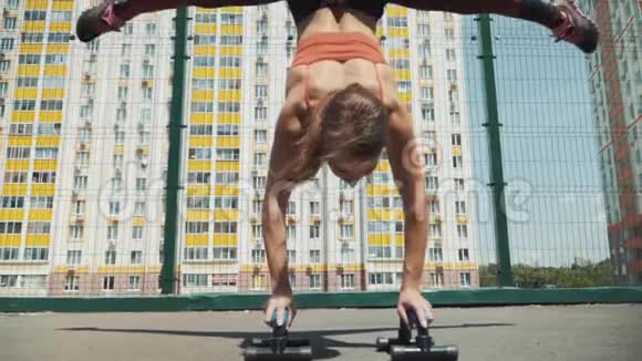 年轻的运动女孩做练习倒立和握住分裂在街上训练健身和伸展视频的预览图