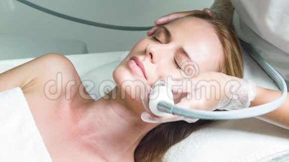 熟练美容师用特殊设备治疗女性面部视频的预览图