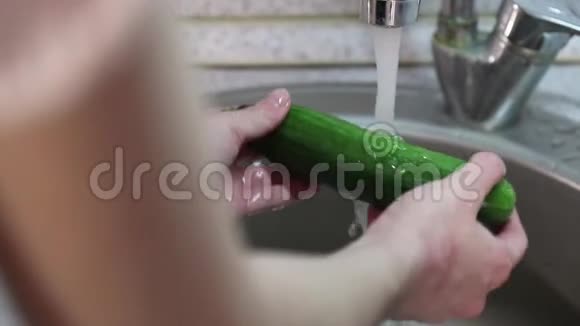女孩在厨房里洗和冲洗新鲜黄瓜视频的预览图