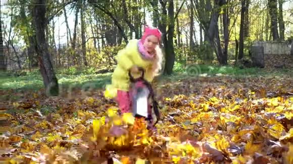小女孩拿着吹叶器在花园里吹秋叶视频的预览图