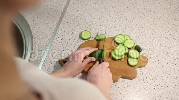 一个年轻女孩的手紧紧地在木板上割黄瓜视频的预览图