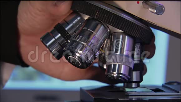 一个人的手在实验室的显微镜上转动一个镜头视频的预览图