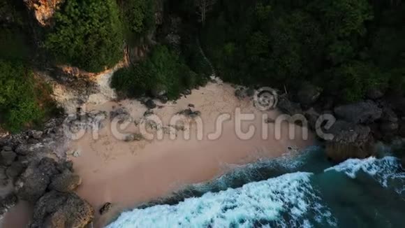 无人机顶景向上移动远离海洋蓝色波浪撞击海岸线悬崖金沙和干净的海滩视频的预览图