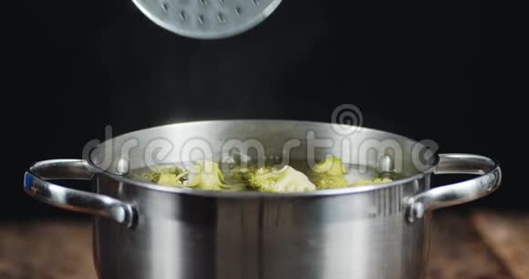 从锅里拿出一个开槽勺子准备西兰花视频的预览图