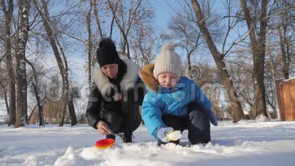 小男孩和他妈妈在雪地公园玩得很开心快乐的家庭在冬天玩雪活跃的冬季游戏视频的预览图