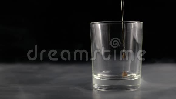 在灰色桌子上的杯子里倒着一杯可乐背景上倒着可乐视频的预览图