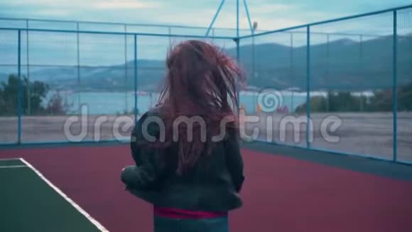 一个美丽而充满激情的女孩跑在篮球或网球场上一位年轻女子在运动场上跑步视频的预览图