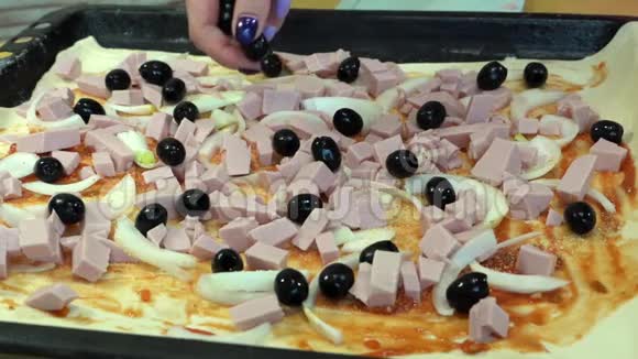 有修指甲的女人把橄榄扔在桌上的披萨上视频的预览图