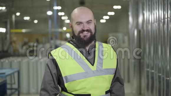 秃顶白种人站在仓库里看着相机微笑着的肖像他的快乐工作者视频的预览图