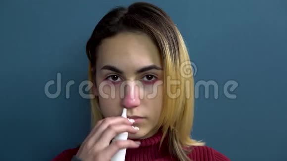一个年轻的女人用鼻子喷感冒药那个女孩用纸巾吹鼻子特写视频的预览图