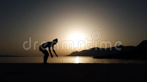 在海上日落时用瑜伽体式平衡双手的强壮女孩视频的预览图