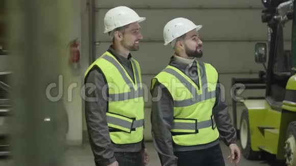 两个白人男子站在仓库和谈话的侧写在生产现场工作的员工工厂视频的预览图