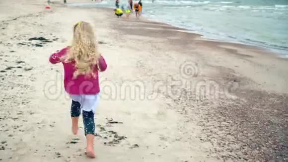 金发女郎穿过海岸线海岸漂亮活泼的孩子玩得开心视频的预览图