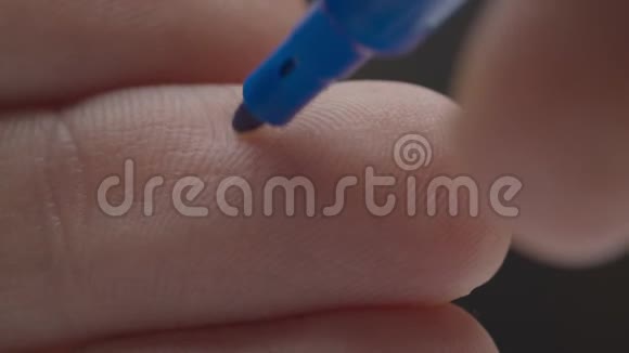 在手指垫上写着蓝色快乐的微笑宏观的看法用蓝色标记在手指上画快乐的表情符号视频的预览图