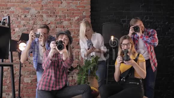 手持不同数码相机的年轻摄影师微笑着在砖墙的背景上拍照视频的预览图