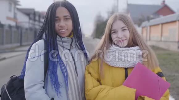 两个漂亮女孩看着相机微笑的肖像白人和非裔美国人在户外摆姿势视频的预览图