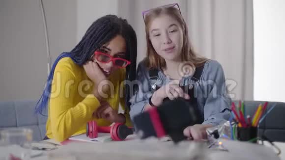 积极的年轻朋友在自拍镜头前谈笑风生白种女孩和她的非洲裔美国红衣朋友视频的预览图