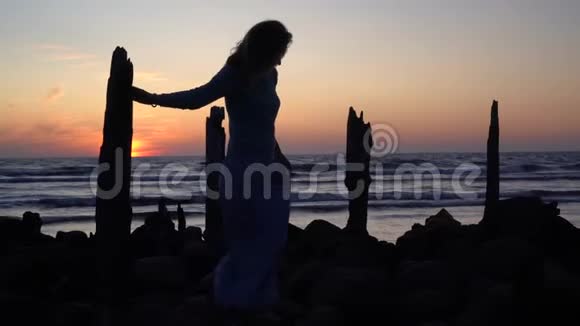 日落时分穿着裙子穿过旧码头的女人剪影视频的预览图