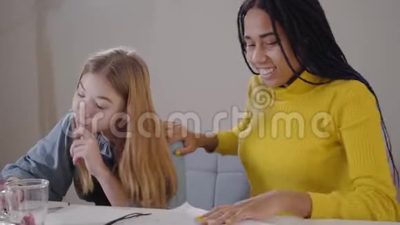 白人女孩做家庭作业作为她的非裔美国朋友做胜利手势的肖像两个学生视频的预览图