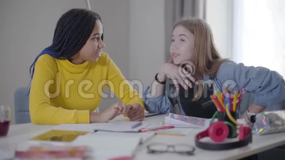 漂亮的白种女孩在感情上对非裔美国朋友说些什么快乐的学生坐在桌边视频的预览图