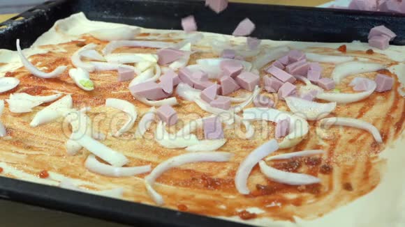 慢动作手把香肠扔在生披萨面团上放在洋葱和沙司上视频的预览图