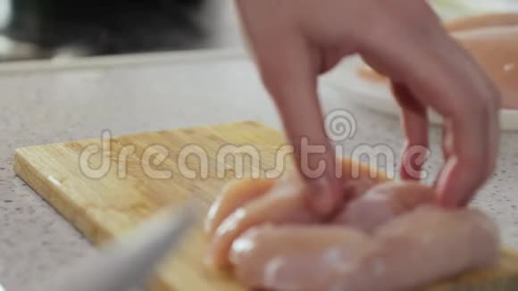一个年轻女孩的手把切鱼片的鸡放在木板上视频的预览图