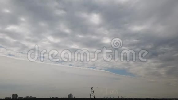 天空时间流逝地平线上的城市景观上有戏剧性的云前景上的输电塔顶部视频的预览图