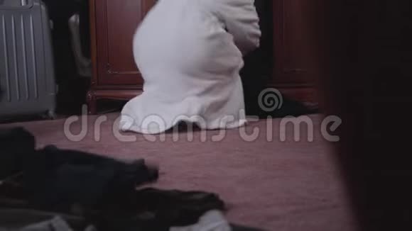 在浴袍前看到女性白种人的腿穿着白色浴袍扔衣服的年轻女子视频的预览图
