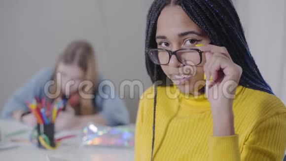 一位美丽的非洲裔美国妇女看着相机拿着眼镜穿黄色毛衣的可爱女孩视频的预览图