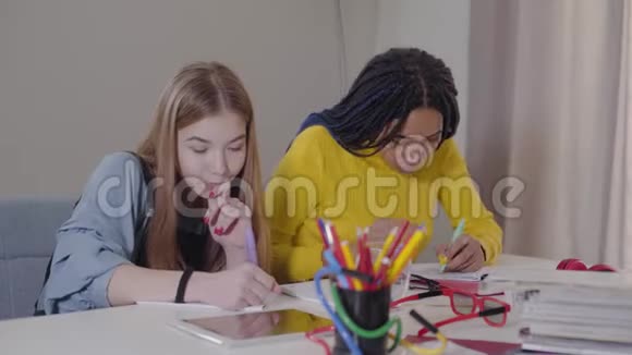 侧面看两个朋友在家做作业非洲裔美国女孩做胜利的手势给高五视频的预览图