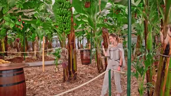 高加索女性博客影响者通过智能手机在社交媒体上广播在香蕉种植园里种树视频的预览图