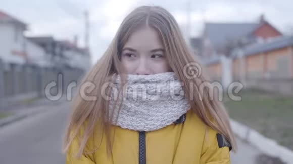穿着黄色外套和白色围巾站在户外的可爱高加索女孩的肖像像看摄像机一样的漂亮少年视频的预览图