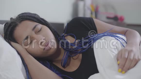 非洲裔美国女孩的特写脸睡觉和固定白色毯子在家休息的有恐惧症的青少年视频的预览图