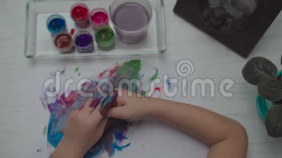 孩子们用彩色颜料在白纸上画画儿童手指画的俯视图视频的预览图