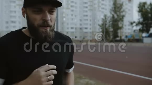 年轻动力的蓄胡子男运动员在赛道上奔跑的电影特写镜头引领健康的生活方式慢动作视频的预览图