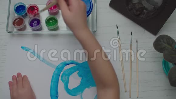 孩子们用彩色颜料在白纸上画画儿童画笔绘画的俯视图视频的预览图