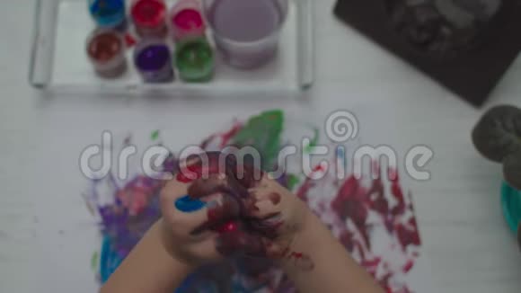孩子们用彩色颜料在白纸上画画儿童手指画的俯视图视频的预览图