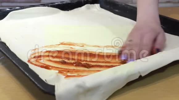 手工在面团上涂抹番茄酱用来制作披萨视频的预览图